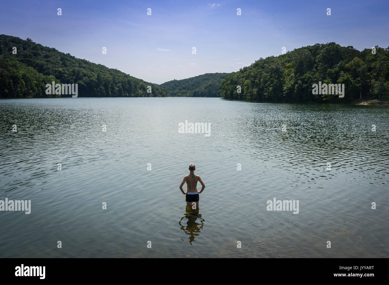Donna con le mani sui fianchi in piedi nel lago Foto Stock
