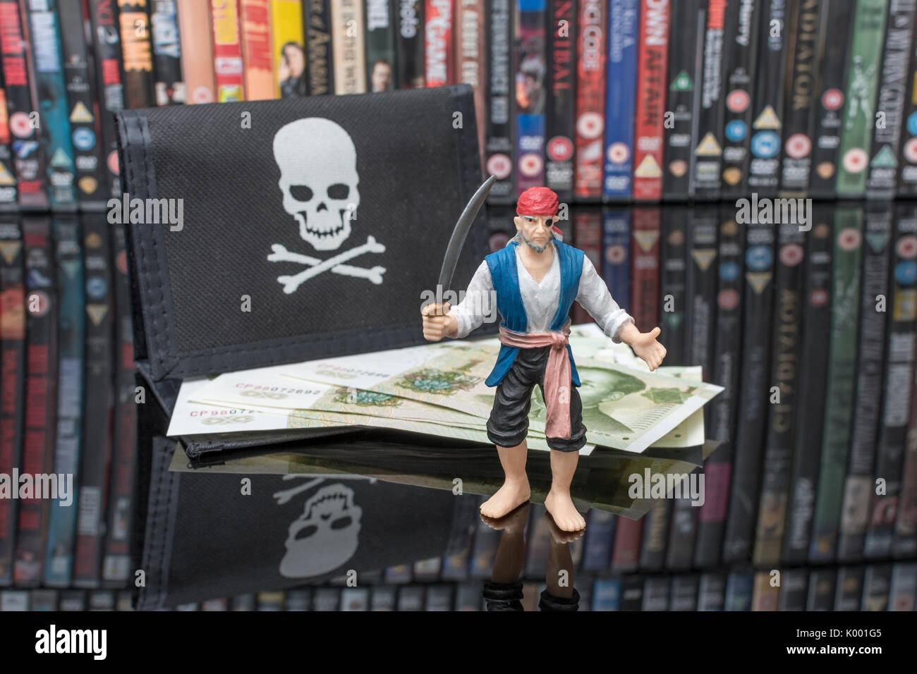 La spada wielding pirata giocattolo in piedi accanto a pile di DVD (Disco versatile digitale) - metafora della pirateria del software, Cinese merci contraffatte e il furto di IP. Foto Stock