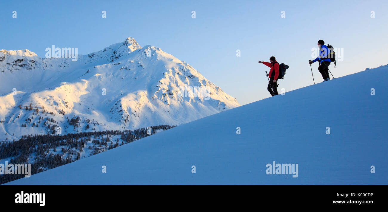 Escursionista con le racchette da neve guarda il Piz de la Margna accesa dall'ultimo sole del giorno. Il Cantone dei Grigioni. Maloja Pass. Engadina. La Svizzera. Europa Foto Stock