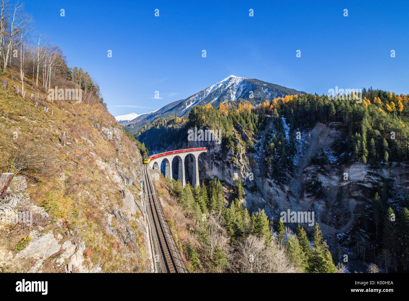 Bernina Express passa attraverso Landwasser Viadukt circondato da boschi colorati nel Canton Grigioni Svizzera Europa Foto Stock