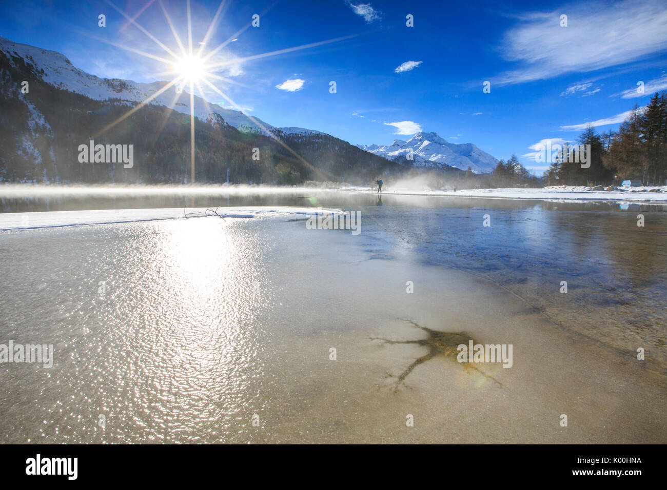 Inverno il sole illumina il lago ghiacciato di Silvaplana circondato da nebbia Maloja Cantone dei Grigioni Engadina Svizzera Europa Foto Stock