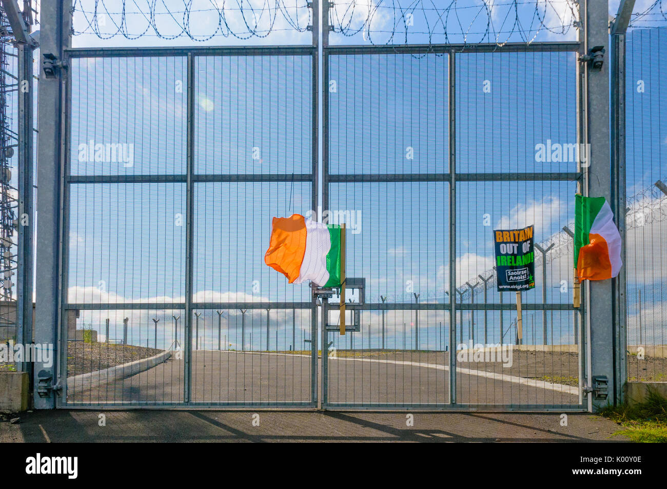Tricolors irlandese e anti-british banner sul gate di un esercito britannico stazione di comunicazione, Belfast Foto Stock