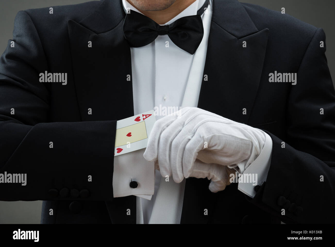 Sezione mediana del mago di eseguire la magia con carte contro uno sfondo grigio Foto Stock