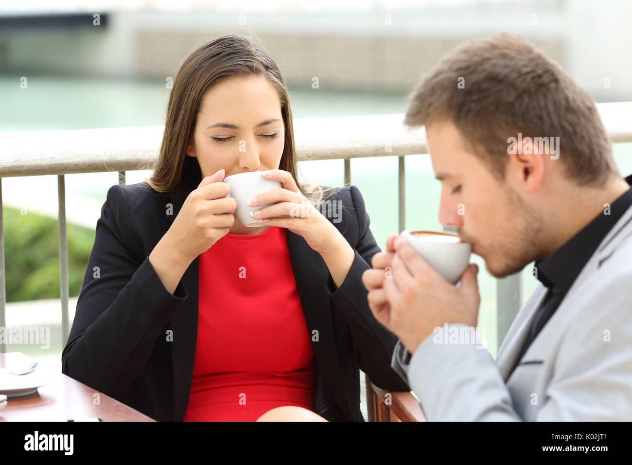 Due dirigenti felice di bere il caffè tazze seduto in un bar terrazza Foto Stock