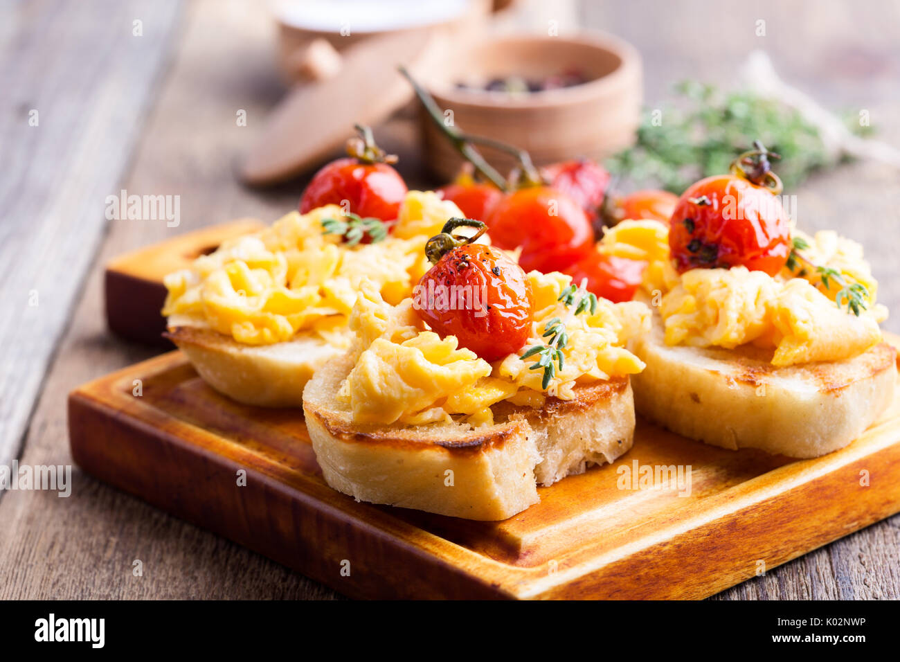 Bruschetta con uova strapazzate e cotta a forno e pomodori ciliegini, delizioso antipasto estivo Foto Stock