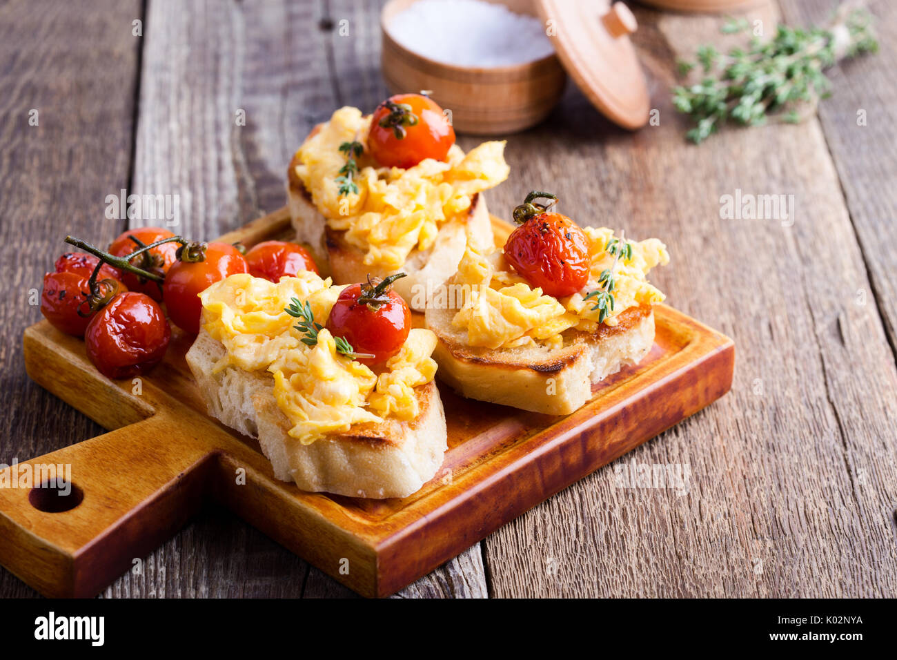 Bruschetta con uova strapazzate e cotta a forno e pomodori ciliegini, delizioso antipasto estivo Foto Stock