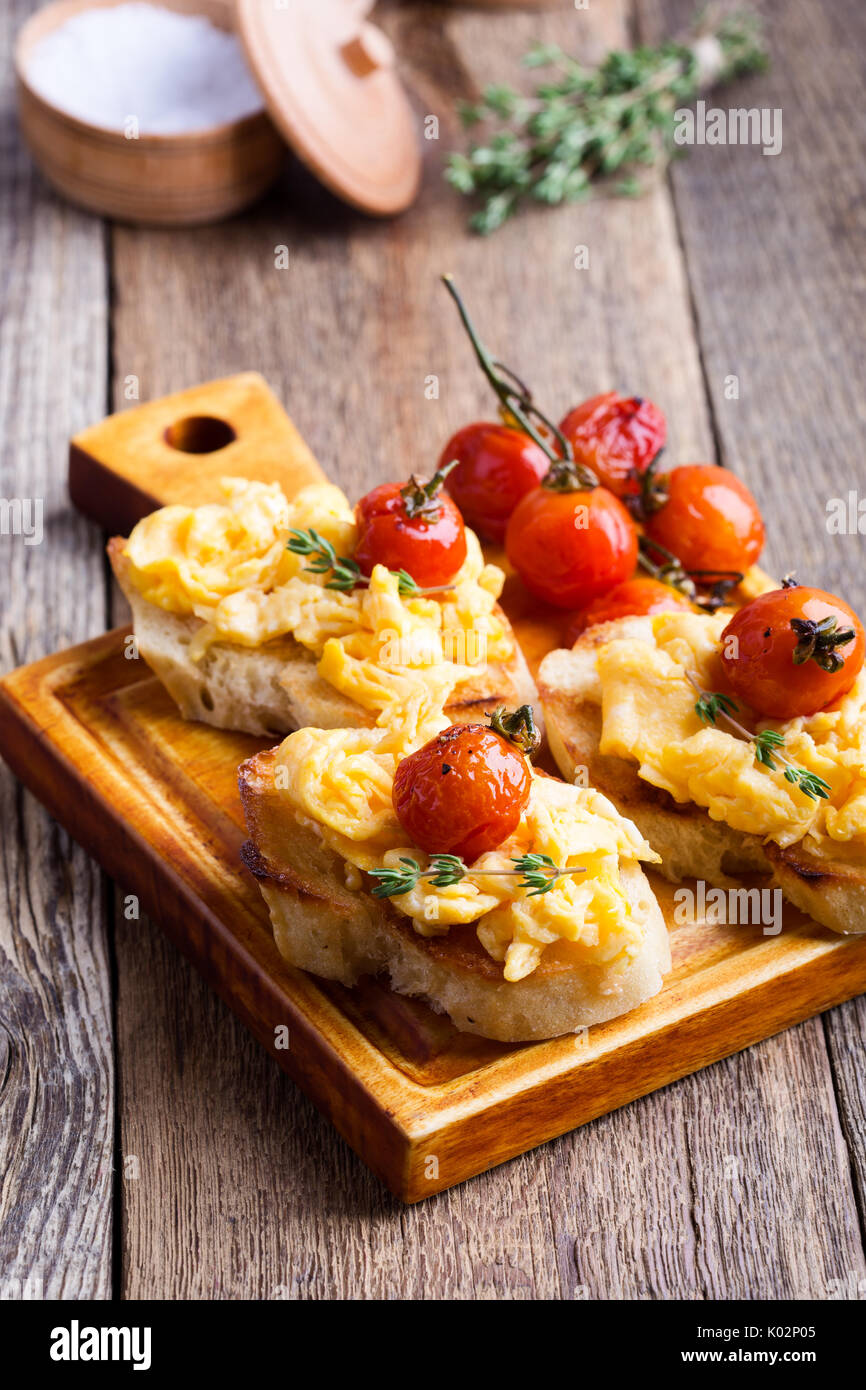 Bruschetta con uova strapazzate e cotta a forno e pomodori ciliegini, delizioso antipasto estivo Foto Stock