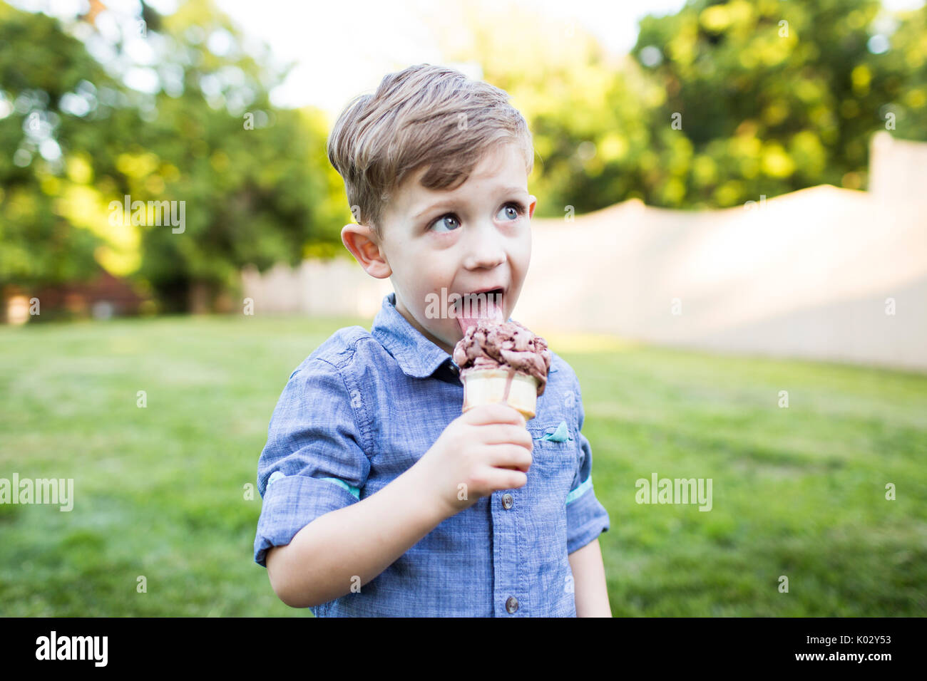 Ragazzo di età prescolare a mangiare il gelato in cono cortile estivo Foto Stock