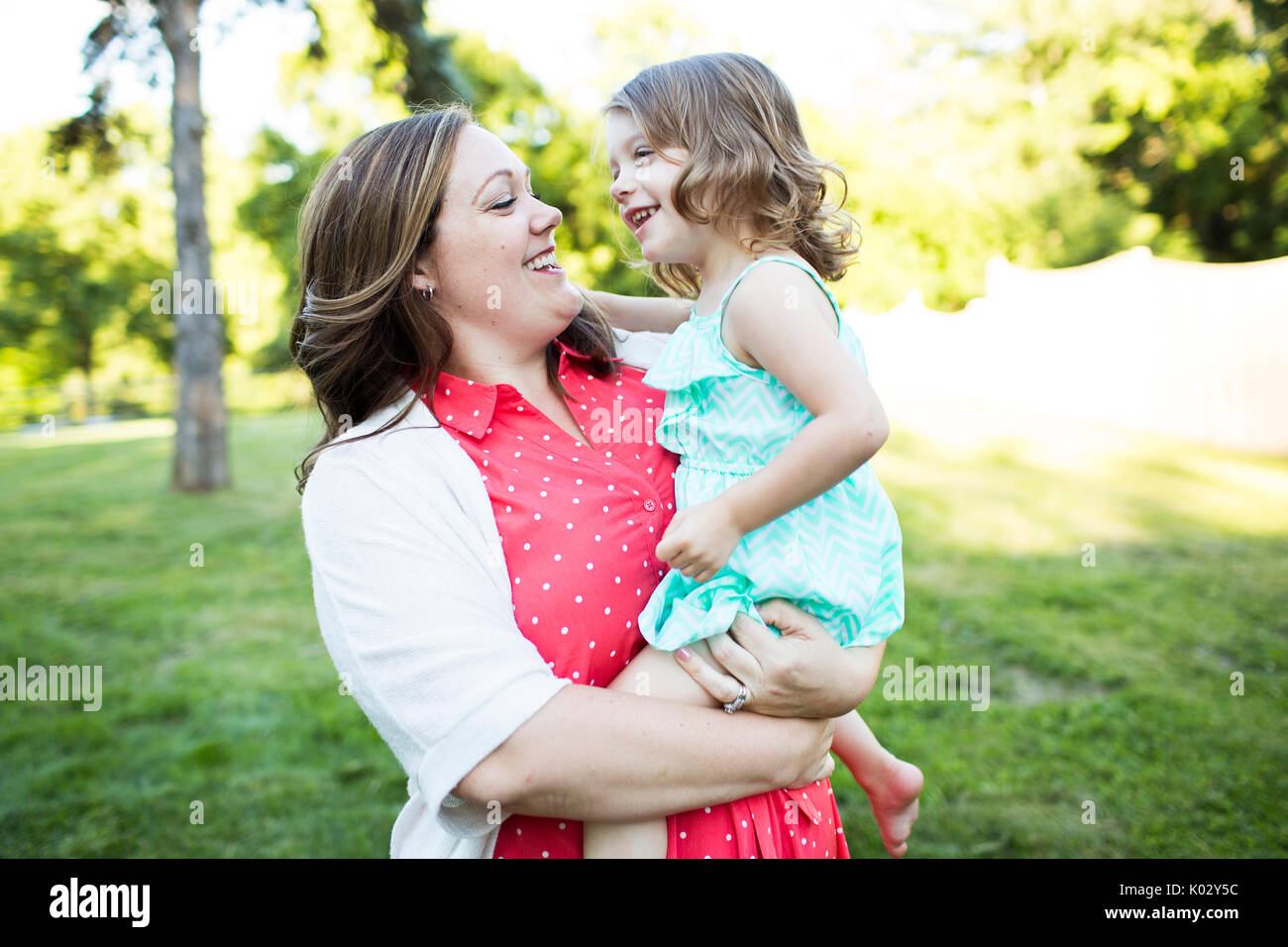 Sorridente e affettuosa Madre figlia di contenimento in estate cantiere di erba Foto Stock