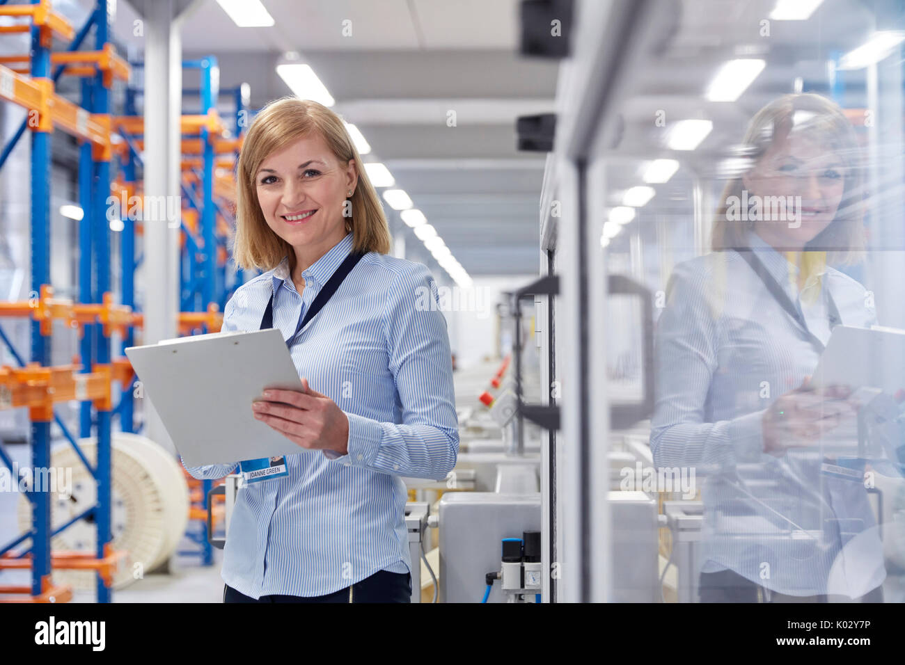 Ritratto di donna sorridente supervisore con appunti in fibre ottiche factory Foto Stock