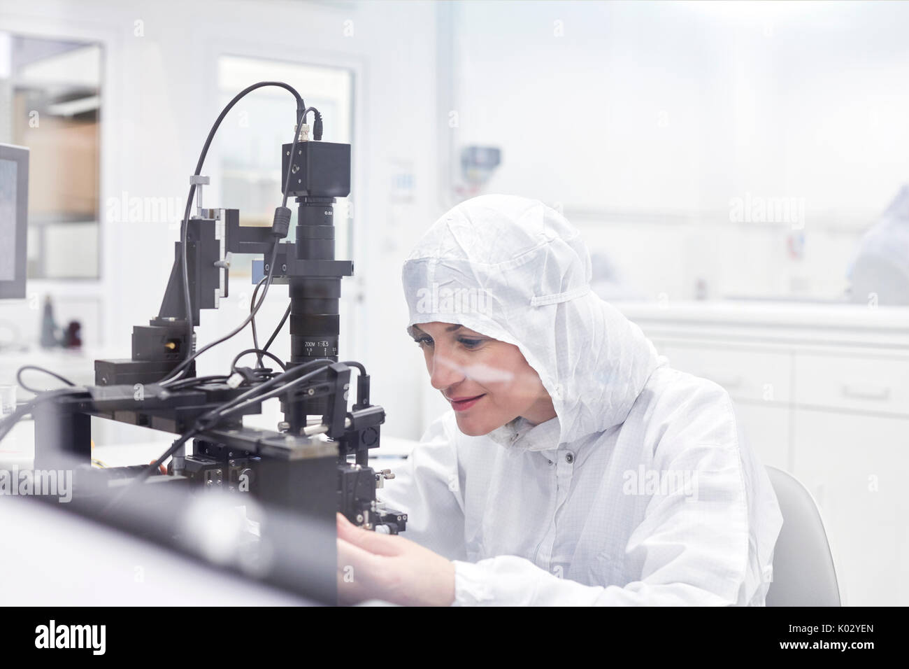 Ingegnere femmina in clean suit utilizzando apparecchiature in fibra ottica di ricerca e di laboratorio di prova Foto Stock