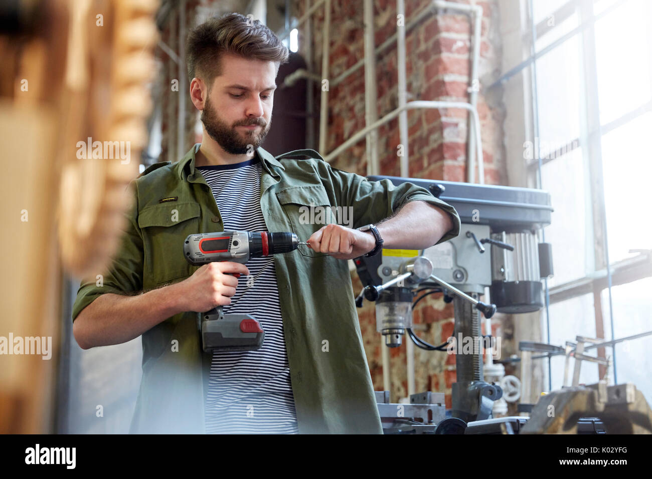 Designer utilizzando il trapano elettrico in officina Foto Stock