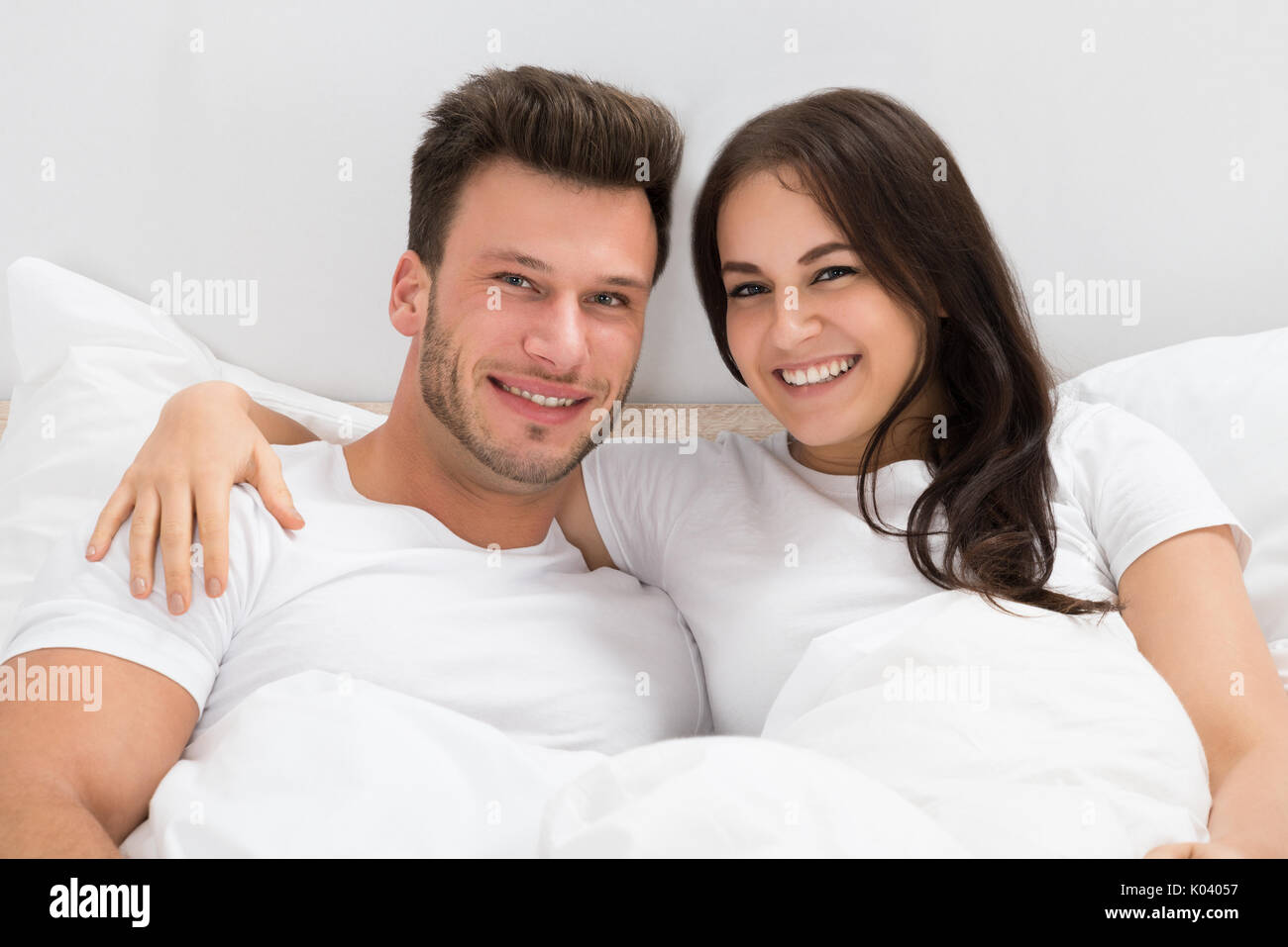 Ritratto di felice coppia giovane sul letto di casa Foto Stock