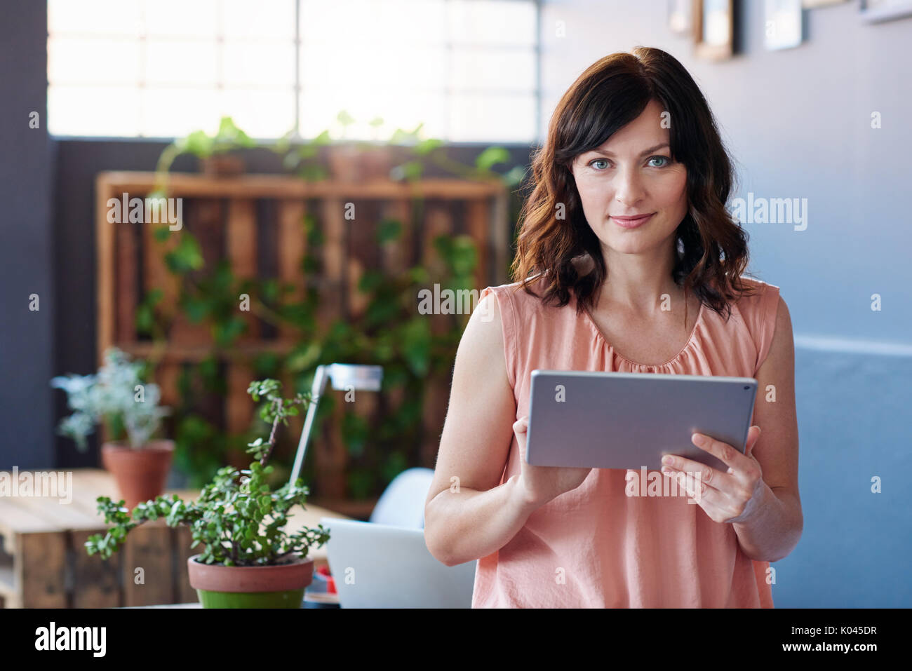Giovane imprenditrice in piedi in un ufficio con una tavoletta digitale Foto Stock