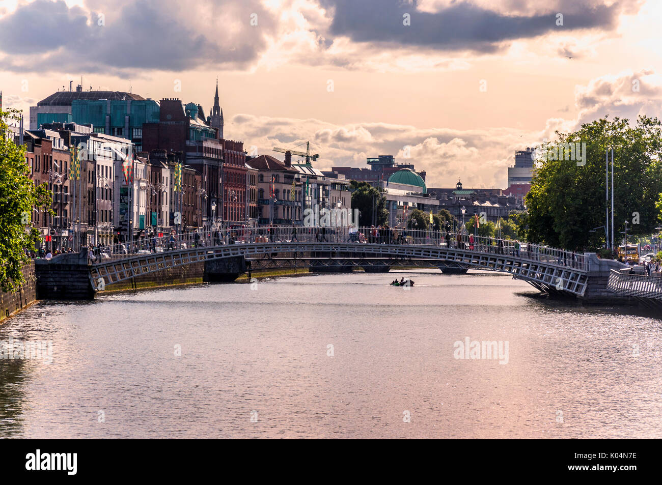 Persone attraversano Ha'penny Bridge attraverso il fiume Liffey nella capitale irlandese di Dublino Foto Stock
