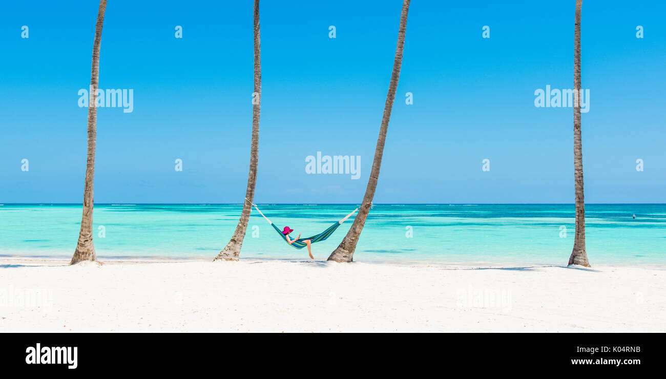 Spiaggia Juanillo (playa Juanillo), Punta Cana, Repubblica Dominicana. Donna relax su una amaca su una spiaggia orlata di palme (MR). Foto Stock