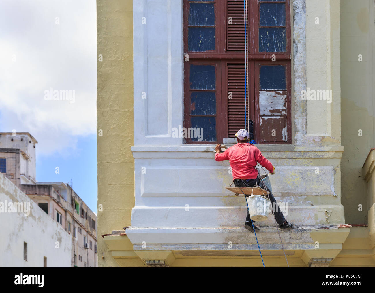 Operaio edile appeso a un edificio sulla fragile cordino in Havana, Cuba Foto Stock