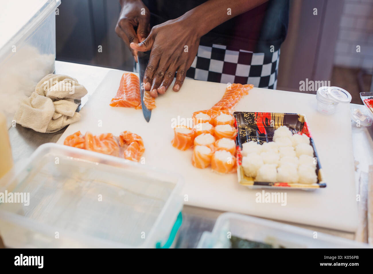 Giovani chef femmina per affettare il salmone, rendendo il sushi al ristorante Foto Stock