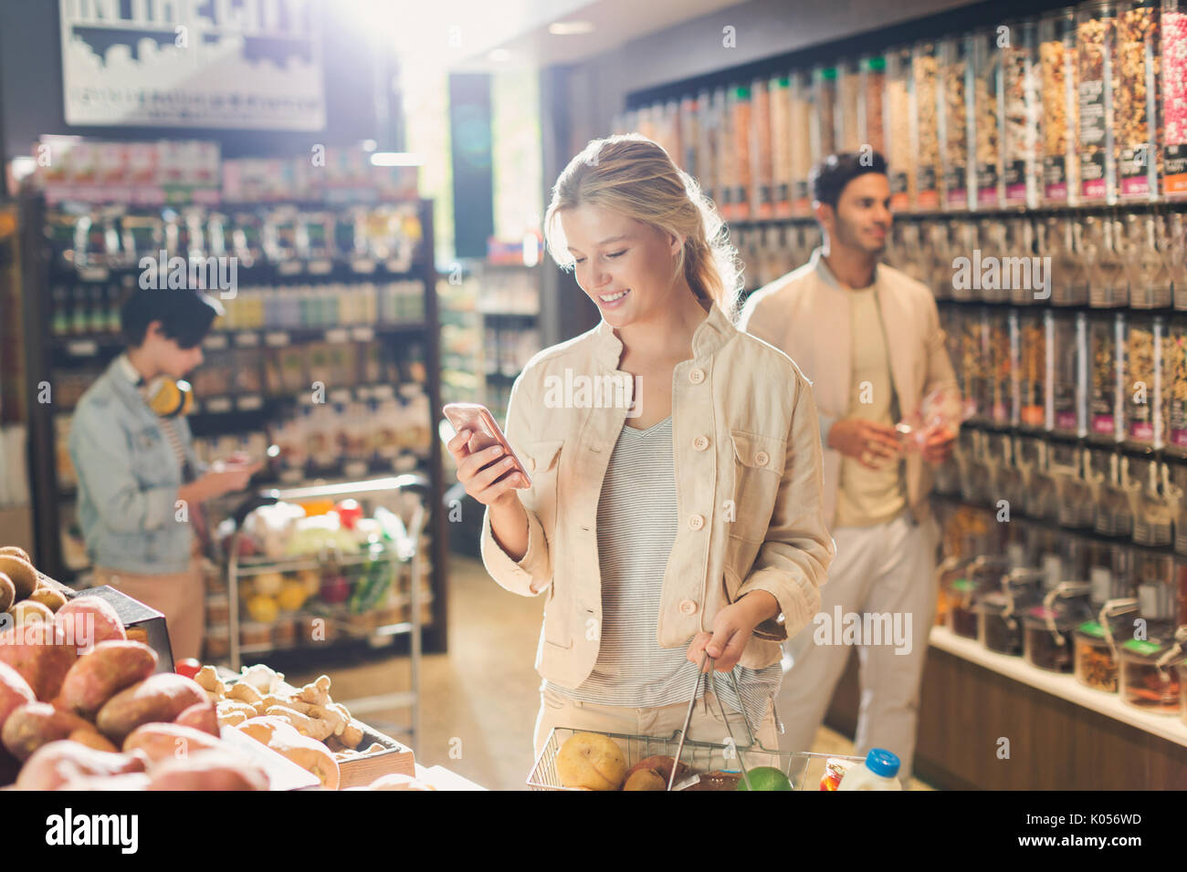 Giovane donna tramite telefono cellulare, spesa nel mercato Foto Stock