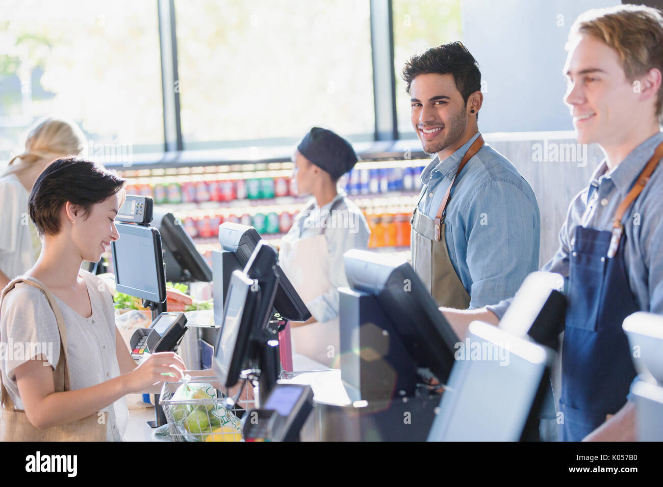 Ritratto sorridente, fiducioso giovane maschio cassiere lavora al negozio di alimentari checkout del mercato Foto Stock