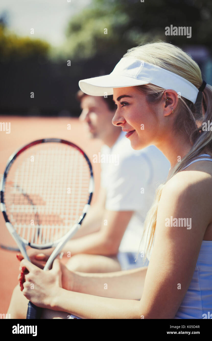 Sorridente, fiducioso femmina giocatore di tennis Racchetta di contenimento sul soleggiato Campo da tennis Foto Stock