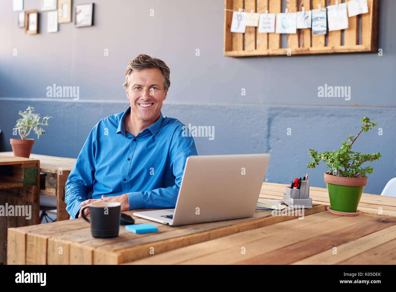 Sorridente imprenditore maturo lavorando su un computer portatile in un ufficio Foto Stock