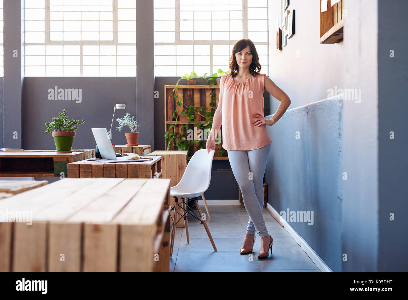 Fiducioso giovane imprenditrice in piedi da solo in un ufficio moderno Foto Stock