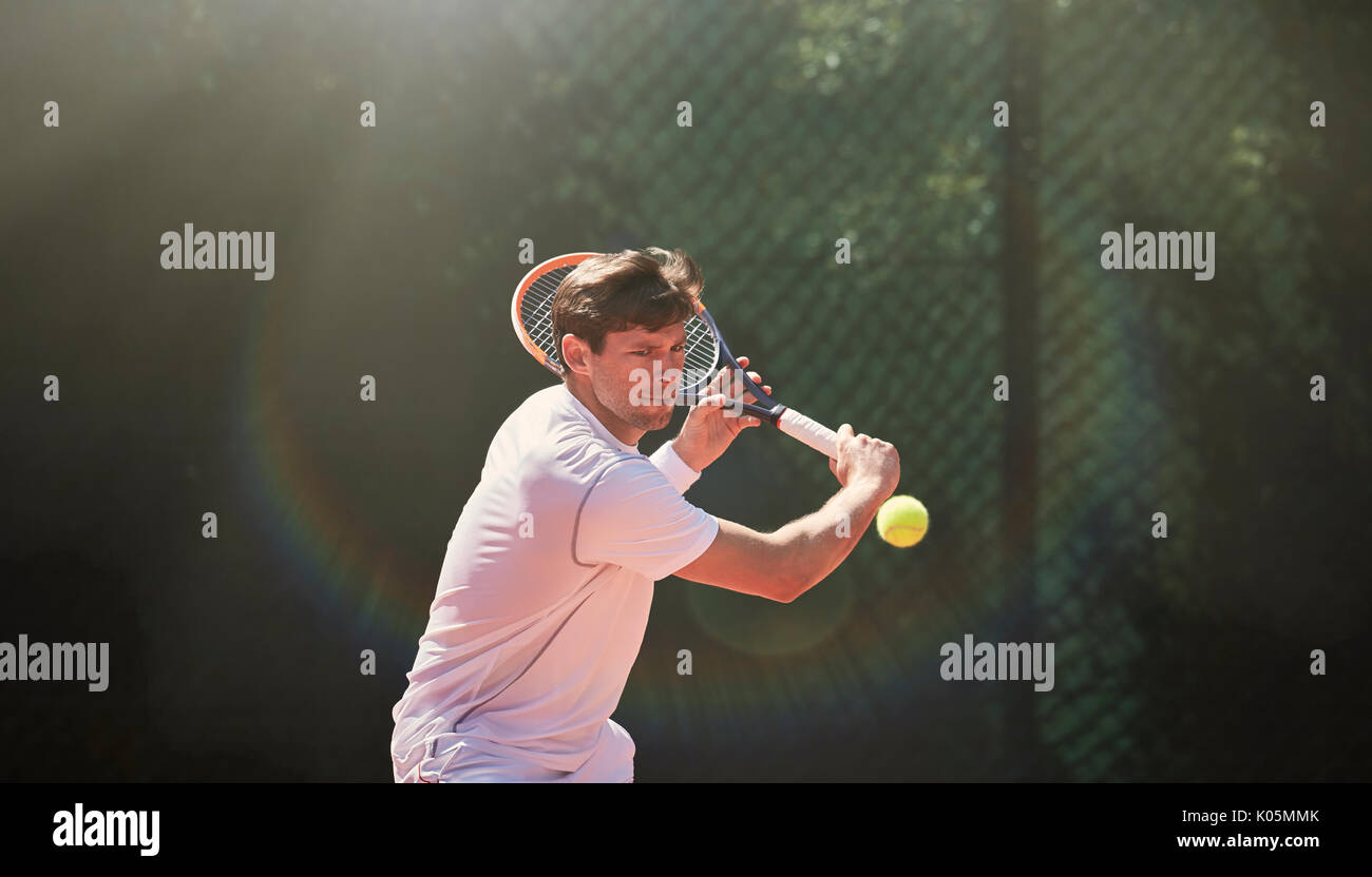 Giovane uomo giocando a tennis, oscillare racchetta da tennis Foto Stock