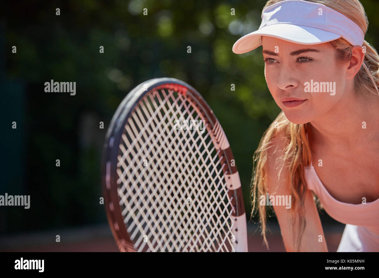 Focalizzato femmina giovane giocatore di tennis holding racchetta da tennis Foto Stock
