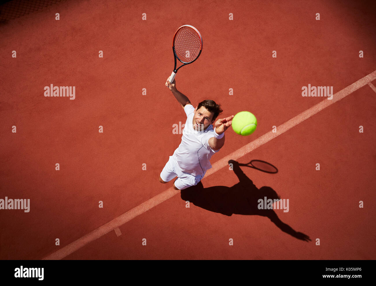 Vista aerea maschile giovane giocatore di tennis giocando a tennis, che serve la sfera sul soleggiato Campo da tennis Foto Stock