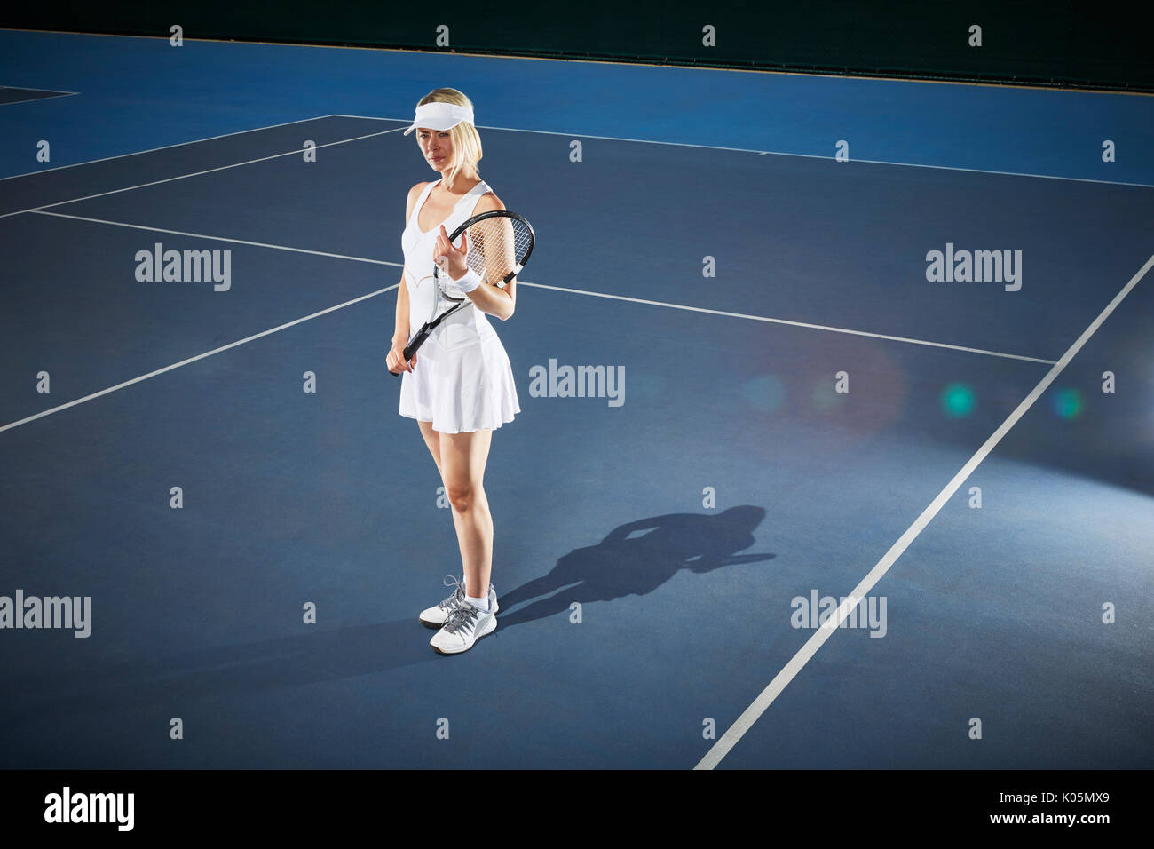 Femmina giovane giocatore di tennis holding racchetta da tennis sul blu soleggiato Campo da tennis Foto Stock