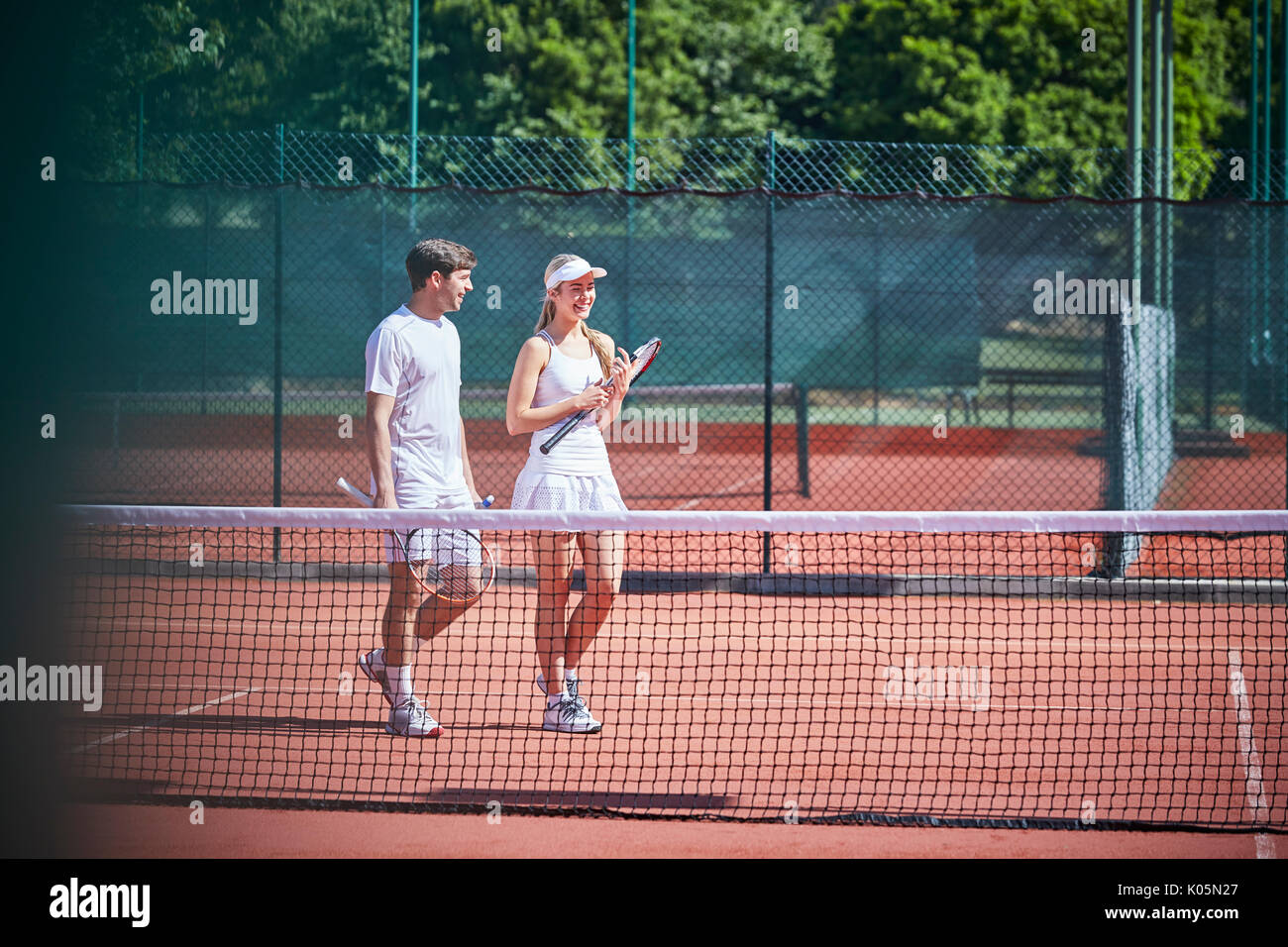 Giovane giocatore di tennis giovane passeggiate con racchette da tennis sul soleggiato Campo da tennis in terra battuta Foto Stock