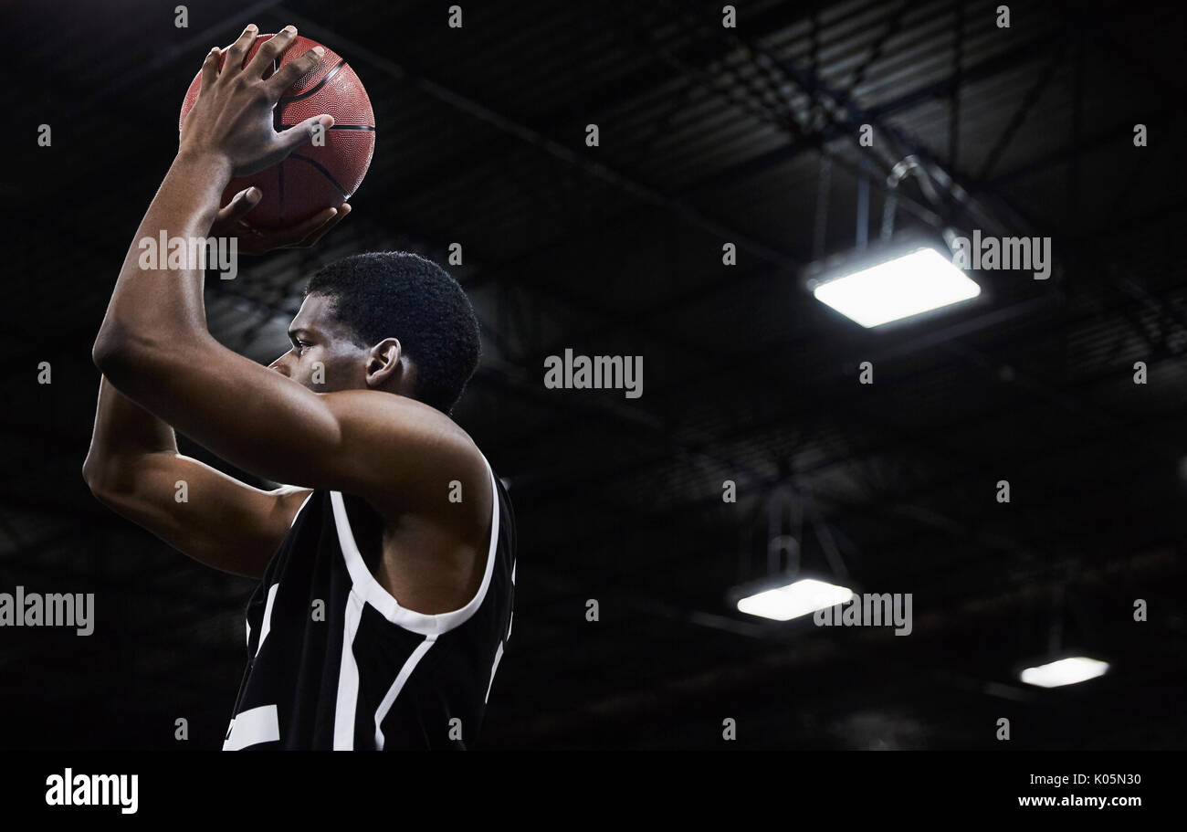 Focalizzato maschile giovane giocatore di pallacanestro di tiro della palla in palestra Foto Stock