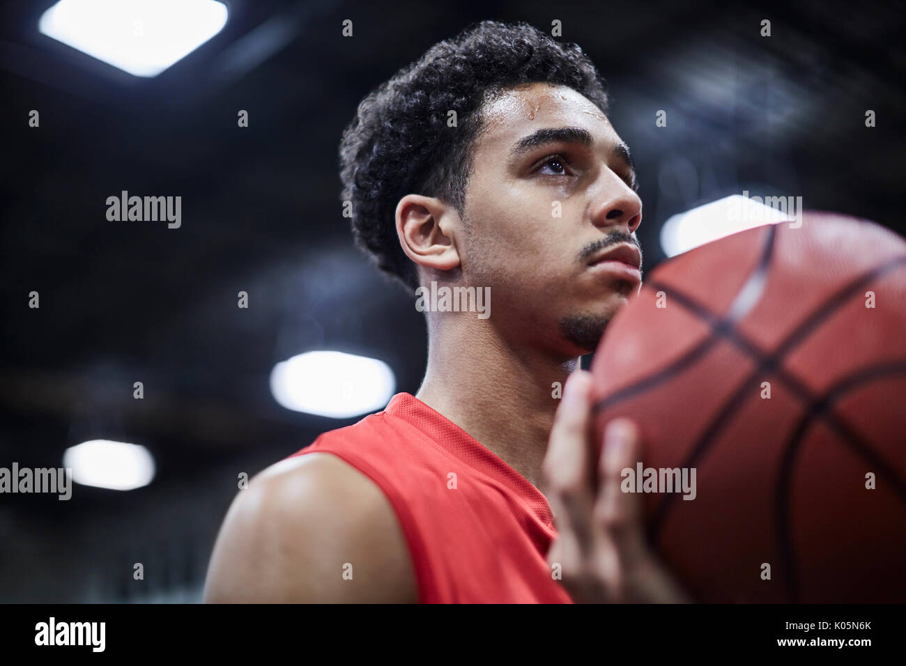 Ritratto di grave, focalizzata maschile giovane giocatore di basket tenendo la pallacanestro Foto Stock