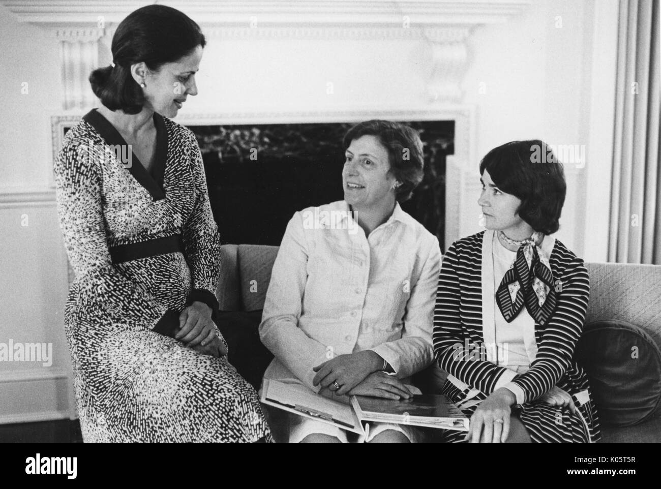 Tre donne seduta su un divano davanti a un caminetto, la donna più a sinistra è seduto sul divano del braccio e la donna al centro è in possesso di un legante sul suo grembo, centennial sferico alla Johns Hopkins University, 1970. Foto Stock