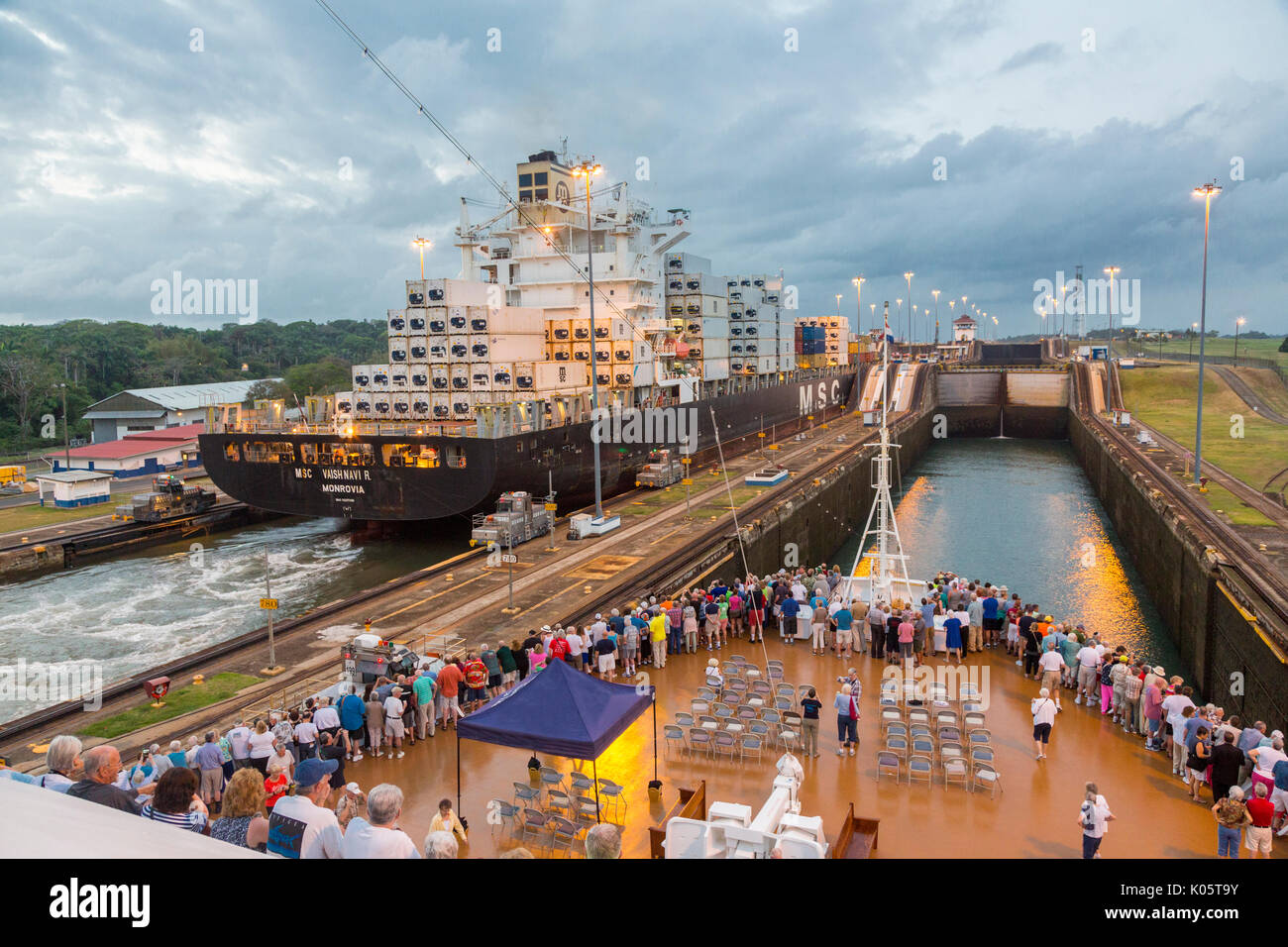 Canale di Panama, Panama. Contenitore nave entrando nel primo blocco, Caraibi, dirigendosi verso il Lago di Gatun, i passeggeri sulla nave da crociera a guardare. Foto Stock