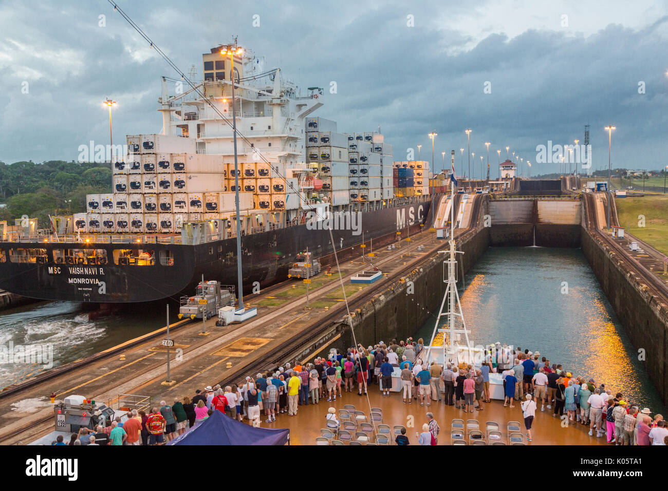 Canale di Panama, Panama. Contenitore nave entrando nel primo blocco, Caraibi, dirigendosi verso il Lago di Gatun, i passeggeri sulla nave da crociera a guardare. Foto Stock