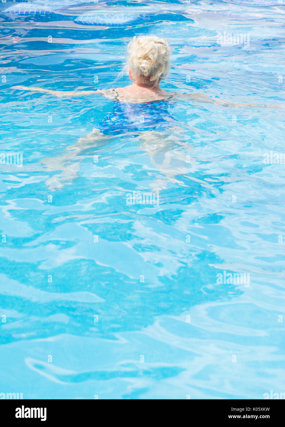 Donna anziana nuoto nella piscina esterna Foto Stock