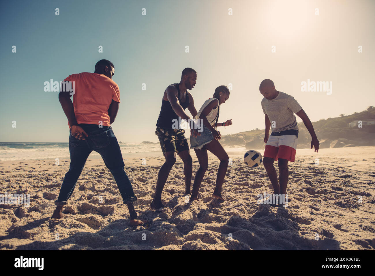 Giovani amici a giocare a calcio sulla spiaggia sabbiosa. Popolo africano godendo di una partita di calcio sul giorno di estate. Foto Stock