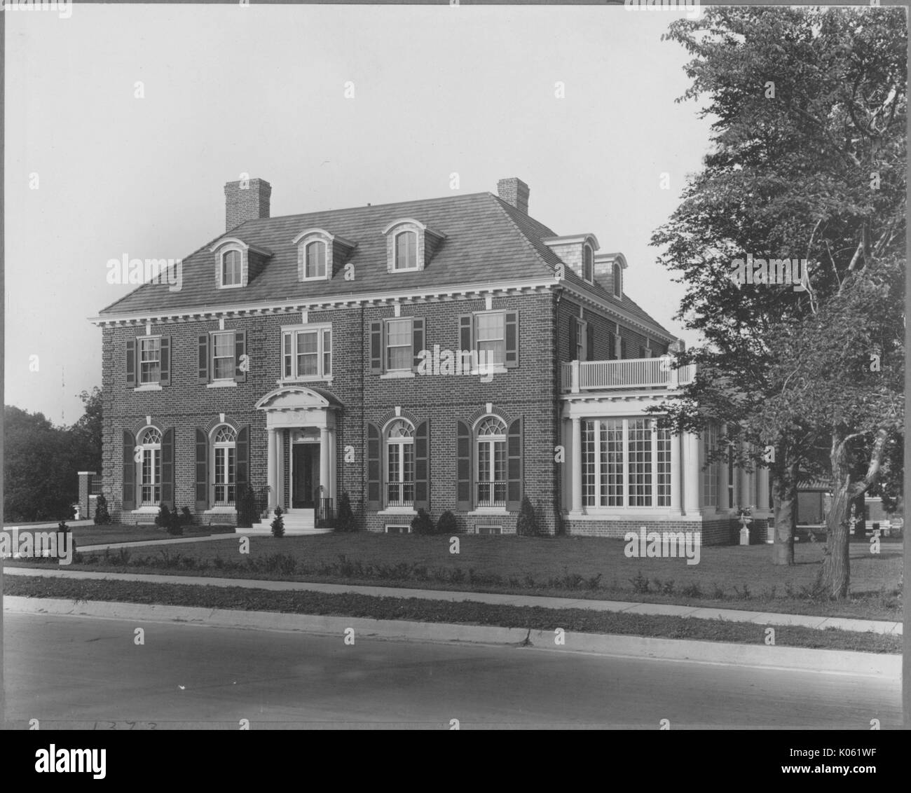 Paesaggio girato a tre piani in mattoni di una casa con un ingresso bianco, bianco allegati sun camera con un balcone sulla parte superiore, un camino, con ben mantenuto arbusteto nel cortile anteriore della casa, due alberi con foglie, Roland parco/Guilford, Stati Uniti, 1910. Questa immagine viene da una serie di documentare la costruzione e la vendita di case nel parco di Roland/Guilford quartiere di Baltimora, un tram sobborgo e una delle prime comunità prevista negli Stati Uniti. Foto Stock