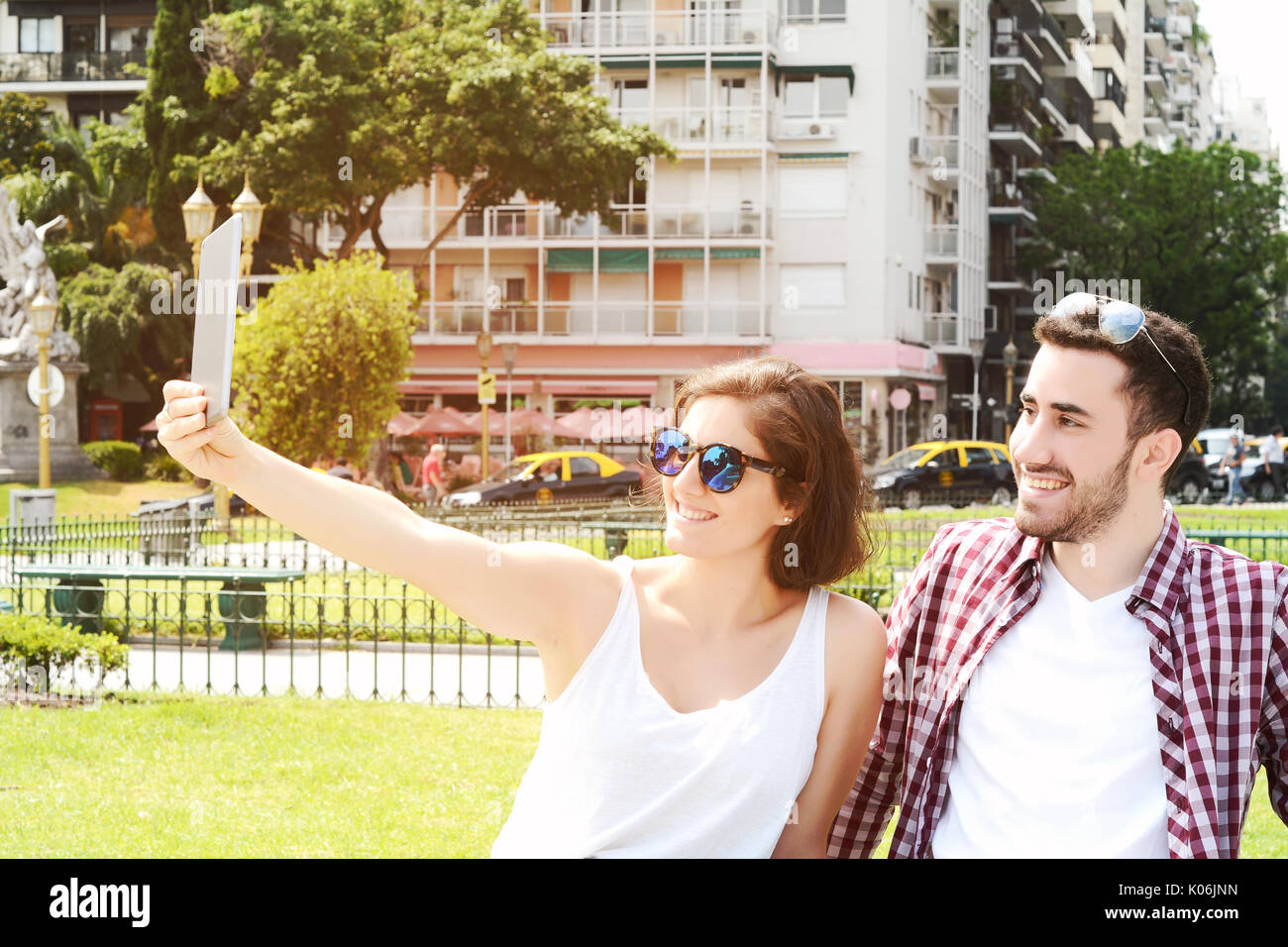 Ritratto di una giovane bella giovane tenendo selfie con tavoletta digitale. All'esterno. Foto Stock