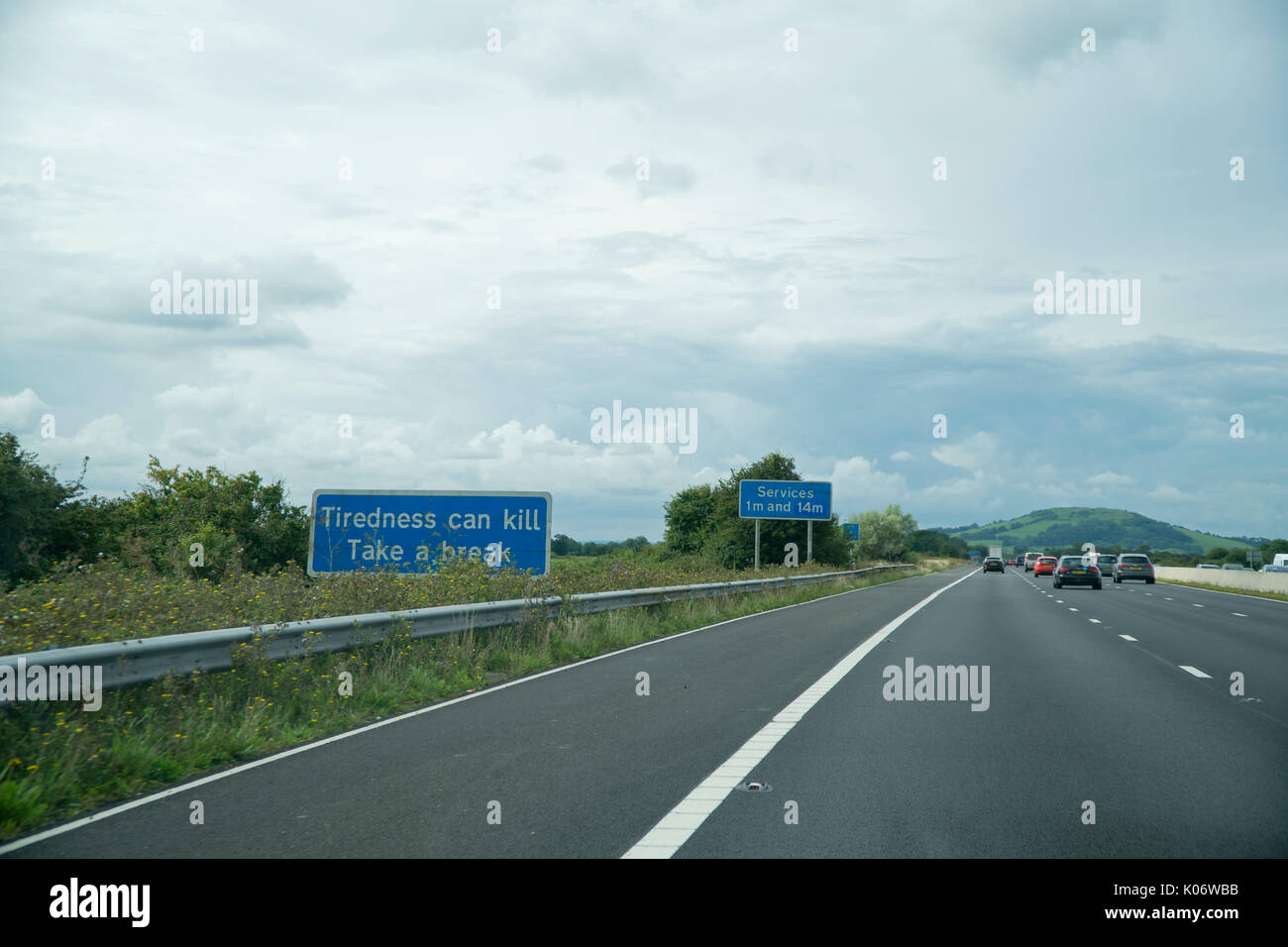 Vista Driver di autostrada in UK con traffico leggero che mostra un segnale di avvertimento la stanchezza può uccidere per prendersi una pausa e servizi in anticipo Foto Stock
