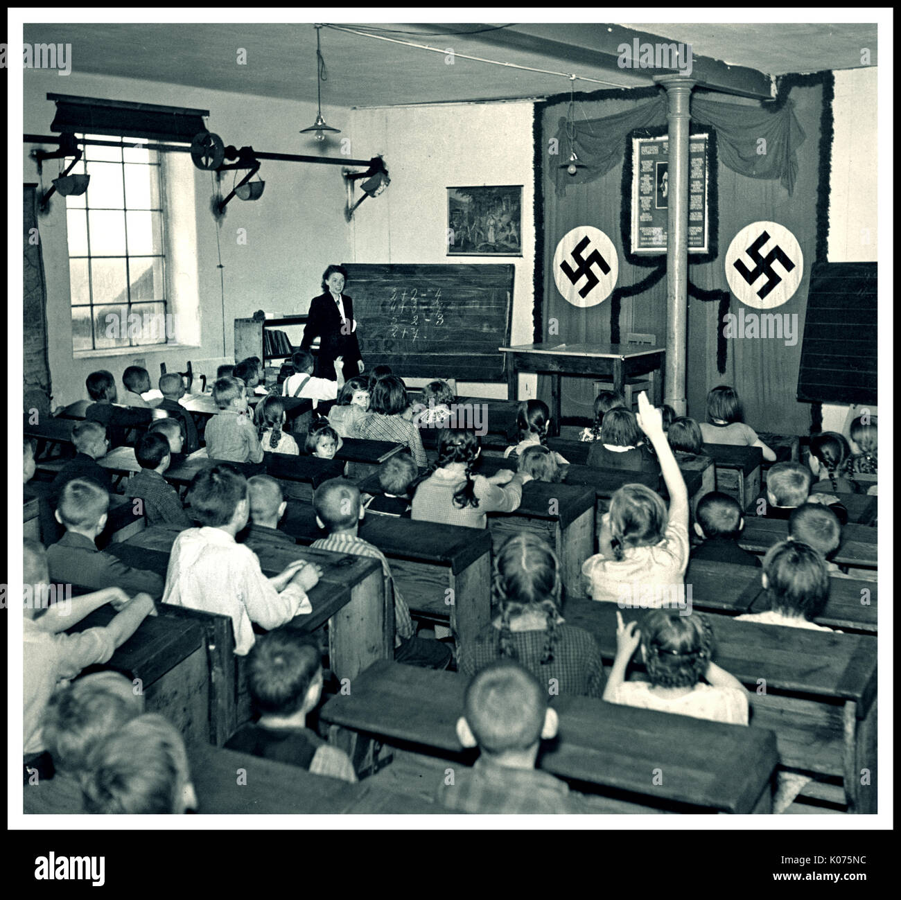 INDOTTRINAMENTO NAZISTA SCUOLA DI SVASTICA PER BAMBINI EMBLEMS ADOLF HITLER SCUOLA di propaganda educazione foto Junior School Classroom with pupil hand up a Leipa, Germania 1940 Foto Stock