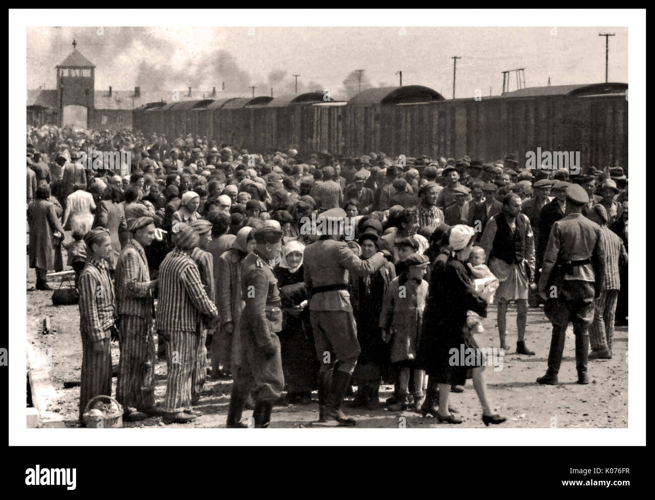 AUSCHWITZ-BIRKENAU PRIGIONIERI DELL'OLOCAUSTO ARRIVO- Una visione starda di un inferno sulla terra. 1944, Nazis 'grading' (vita o morte perentoria) ignari di adulti e bambini arrivati di recente sul convesso ferroviario, fuori l'ingresso al campo di sterminio di Auschwitz-Birkenau. Il famigerato campo di Auschwitz fu iniziato per ordine di Adolf Hitler negli anni '40 durante l'occupazione della Polonia da parte della Germania nazista durante la guerra mondiale del 2, ulteriormente abilitato da Heinrich Luitpold Himmler il Reichsführer dello Schutzstaffel, e membro principale del Partito nazista di Germania Foto Stock