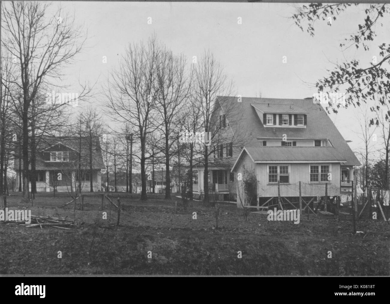 Fotografia di due Roland park homes in Baltimore, entrambi realizzati in laterizio con tetti di grandi dimensioni, uno a due piani con un grande portico, gli altri tre storie e sollevato al di sopra del suolo, entrambe situate da un campo vuoto e alberi con foglie di no, Stati Uniti, 1920. Questa immagine viene da una serie di documentare la costruzione e la vendita di case nel parco di Roland/Guilford quartiere di Baltimora, un tram sobborgo e una delle prime comunità prevista negli Stati Uniti. Foto Stock