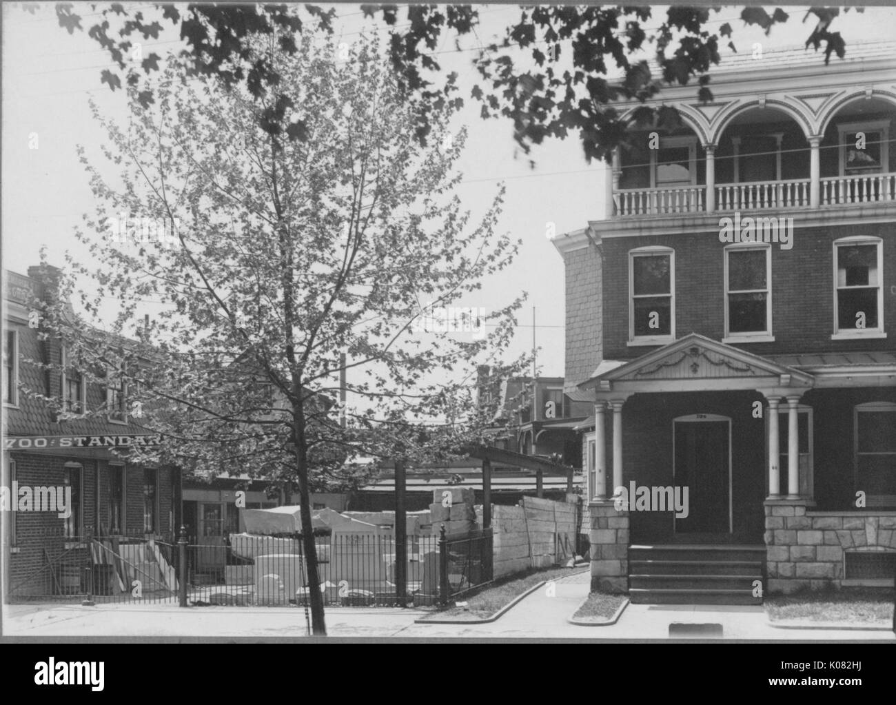 Vista della facciata della multi-story house con la pietra di fondazione su strada tranquilla area di costruzione a sinistra, finestre multiple, una porta, passaggi e colonne che mostrano, portico della ringhiera sul terzo piano, accanto ad albero, Baltimore, Maryland, 1910. Questa immagine viene da una serie di documentare la costruzione e la vendita di case nel parco di Roland/Guilford quartiere di Baltimora, un tram sobborgo e una delle prime comunità prevista negli Stati Uniti. Foto Stock