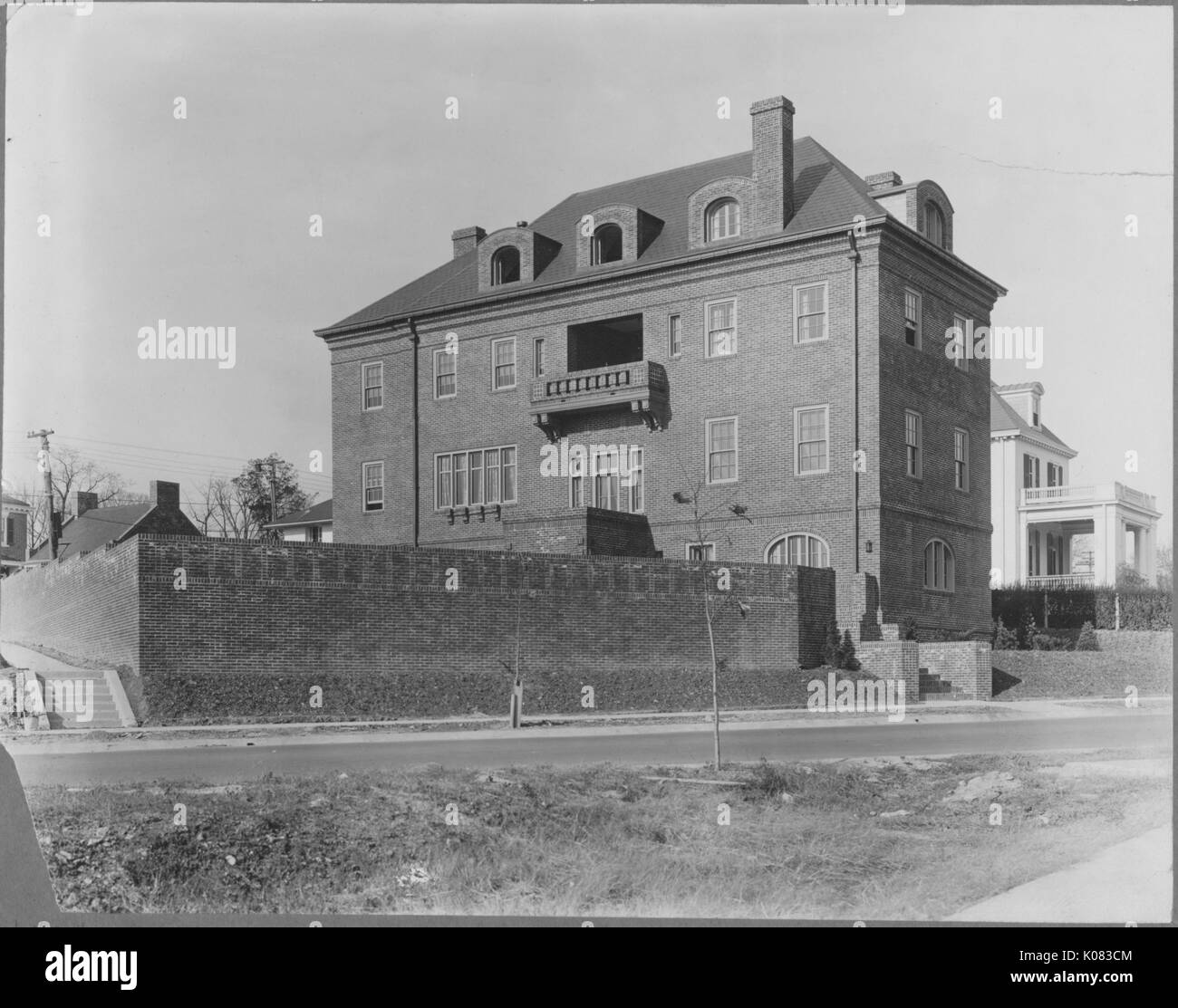 Edificio di quattro piani, in mattoni, balcone sulla terza storia, camino, strada davanti la casa, porticato e balcone di una casa bianca di sfondo visibile; Roland parco/Guilford, Washington DC, 1910. Questa immagine viene da una serie di documentare la costruzione e la vendita di case nel parco di Roland/Guilford quartiere di Baltimora, un tram sobborgo e una delle prime comunità prevista negli Stati Uniti. Foto Stock