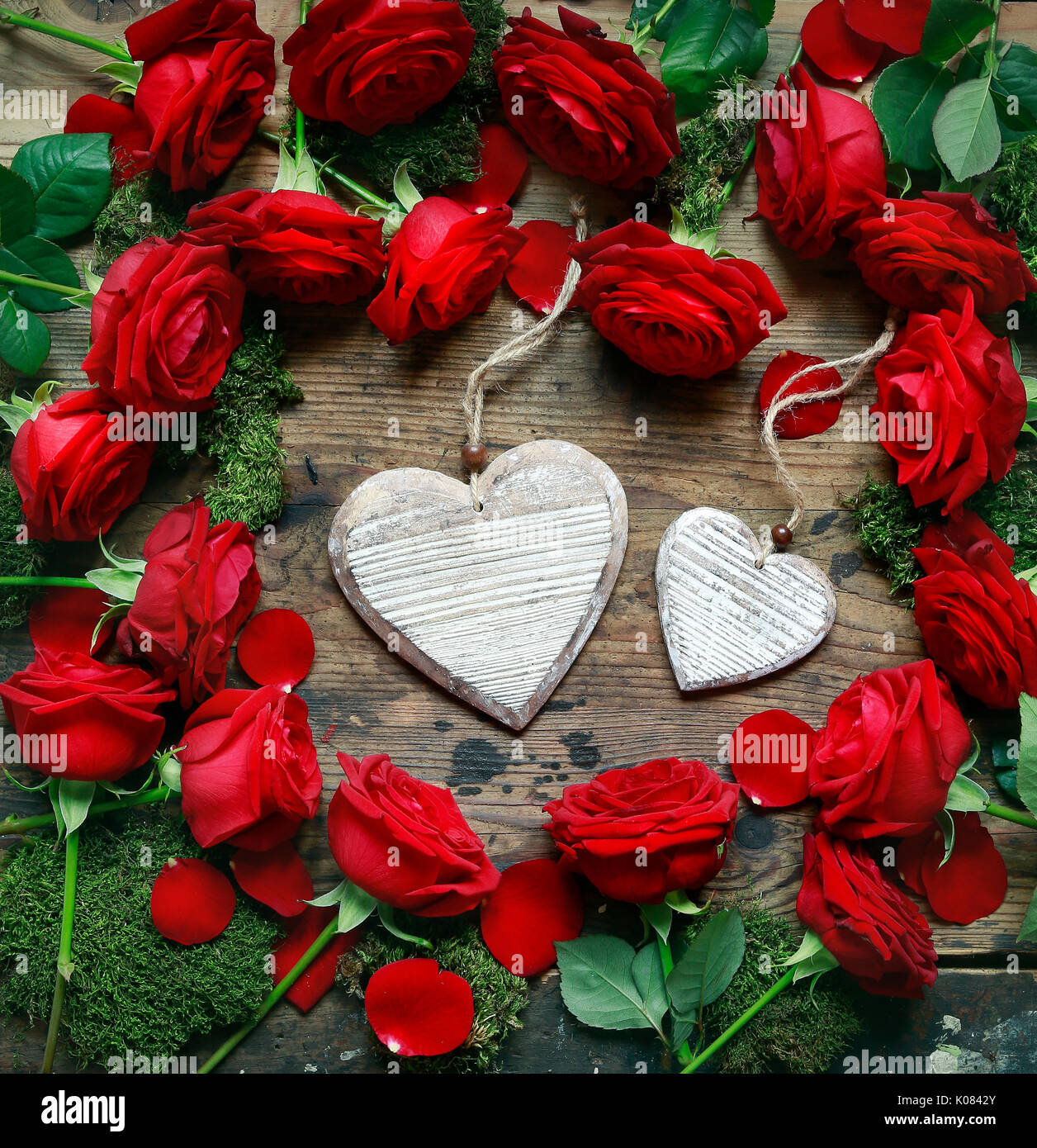 Rose rosse e due cuori su sfondo ligneo. Foto Stock