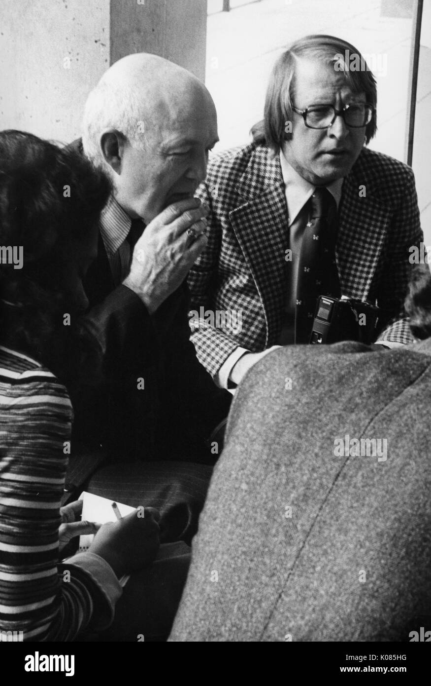 A mezza lunghezza Ritratto di James Coleman, appoggiata sopra la tavola con la sua mano destra sul suo mento, indossando un abito scuro, circondata da altre quattro persone, con un grave espressione facciale, 1970. Foto Stock