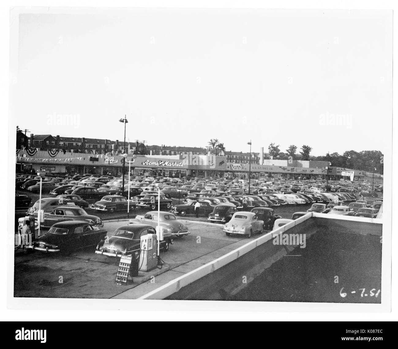 Parcheggio di Northwood Shopping Center con centinaia di automobili, stazione di benzina di fronte foto con diversi negozi in retro terra come Acme mercato, molti alberi e luci di strada in background, Baltimore, Maryland, 1951. Foto Stock